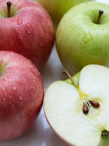 Verse rode en groene appels op een snijplank, gesneden en heel, met appelsap