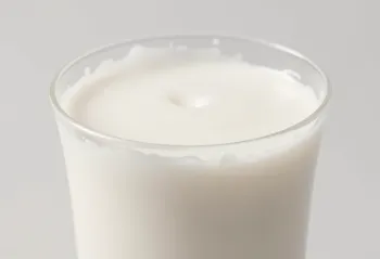 Een glas en een fles verse melk op een licht aanrecht, zonder dieren