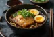 Ramen met gebakken vis, geserveerd met ei, lente-ui en chilipeper