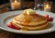 Hotcake geserveerd met ahornsiroop en fruit