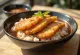 Tonkatsu don, knapperige vleesplakjes op rijst, geserveerd met katsusaus en bosui.