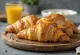 Boterachtige croissantlagen gevuld met ham en gesmolten kaas