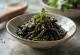 Verse kombu salade geserveerd, bestrooid met sojasaus en sesamzaad