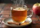 Warme appeldrank met kaneel in een mok, versierd met kaneelstokjes en schijfjes appel